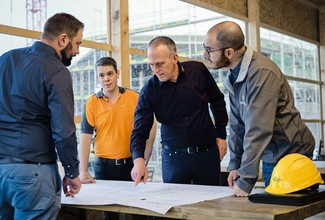 Vier Projektleiter besprechen an einem Tisch Pläne.